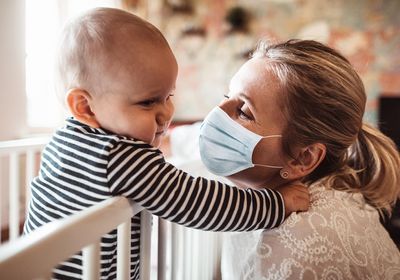 A baby and a caregiver with a face mask.