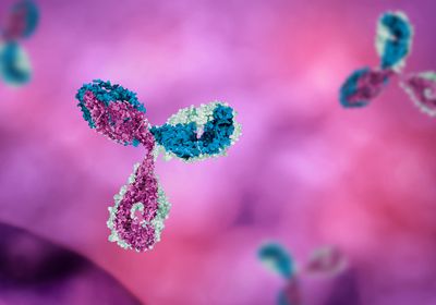 A Y-shaped pink, blue, and light green antibody is in focus on a background of blurred pink and purple color, with other antibodies out of focus in the background.