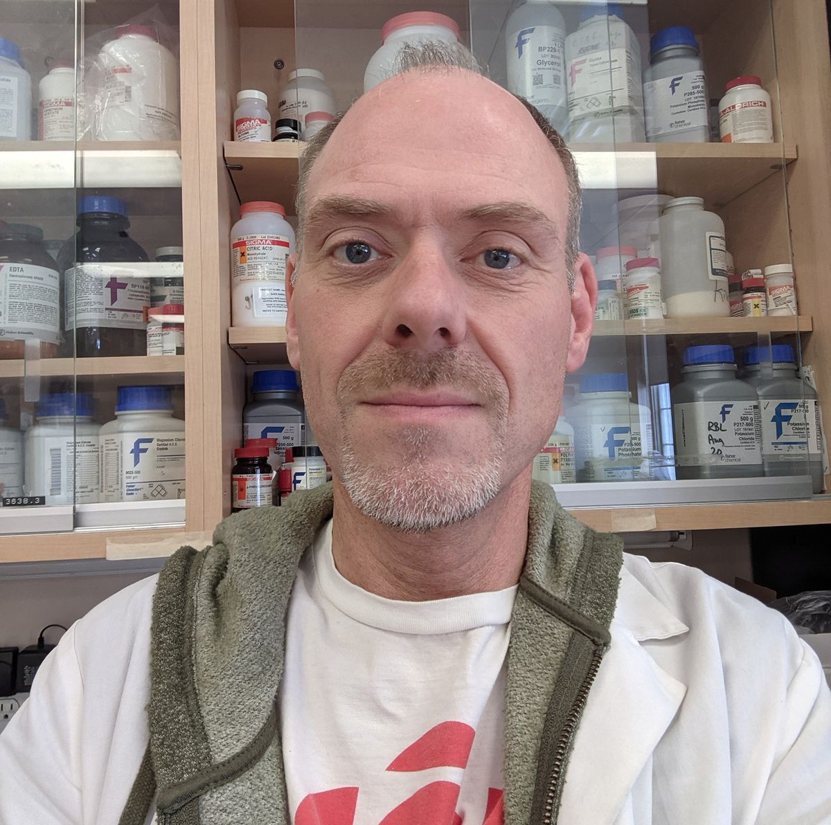 A man stands in front of a cabinet of reagents.