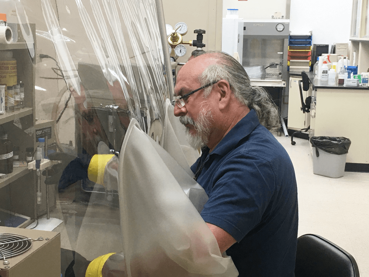 Gary Toranzos handles a test tube inside a sterile chamber.